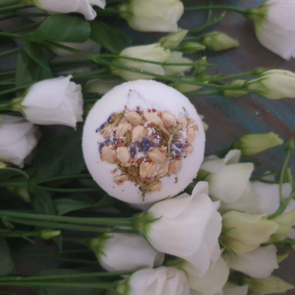 Bath bomb with floral ingredients surrounded by white flowers