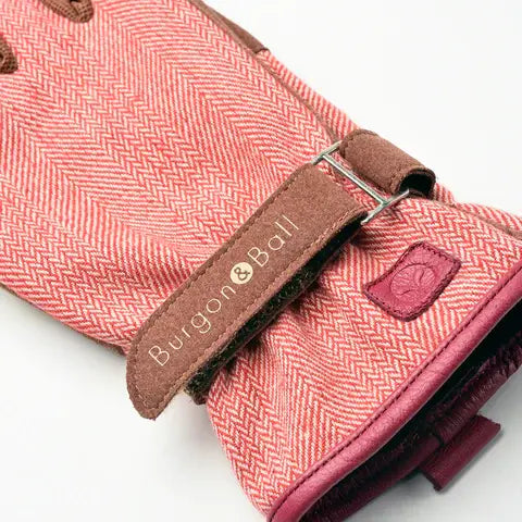 Close-up of a Burgon & Ball tool with pink herringbone pattern and brown leather strap.