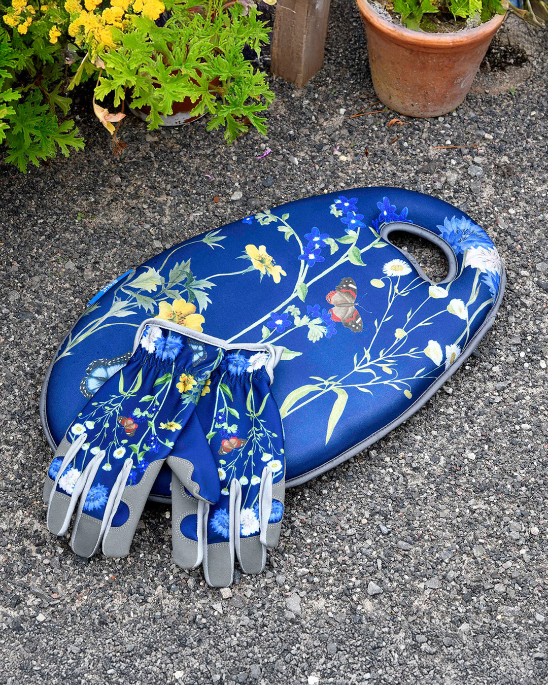 Blue gardening gloves with floral design on a stone surface