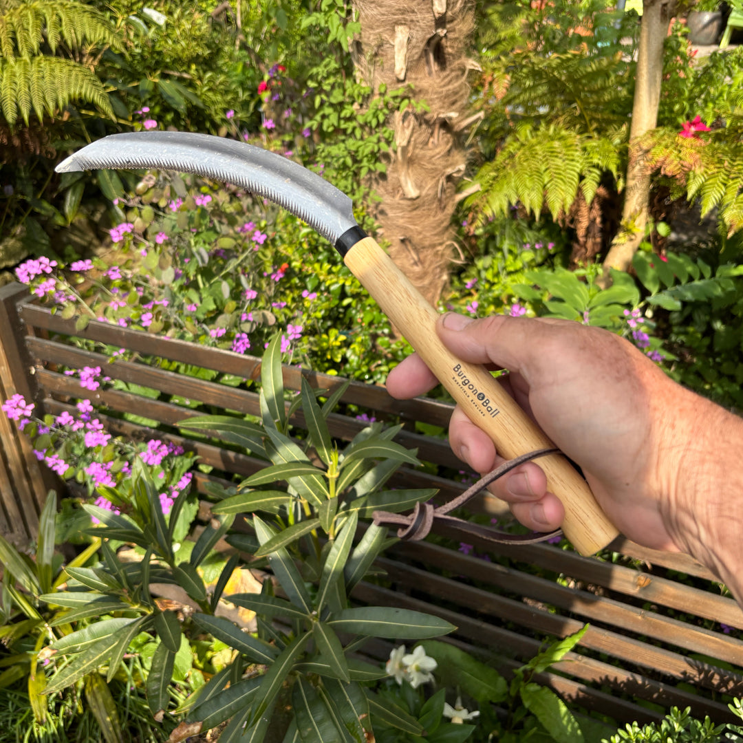 Hand holding a gardening tool with a blurred garden background