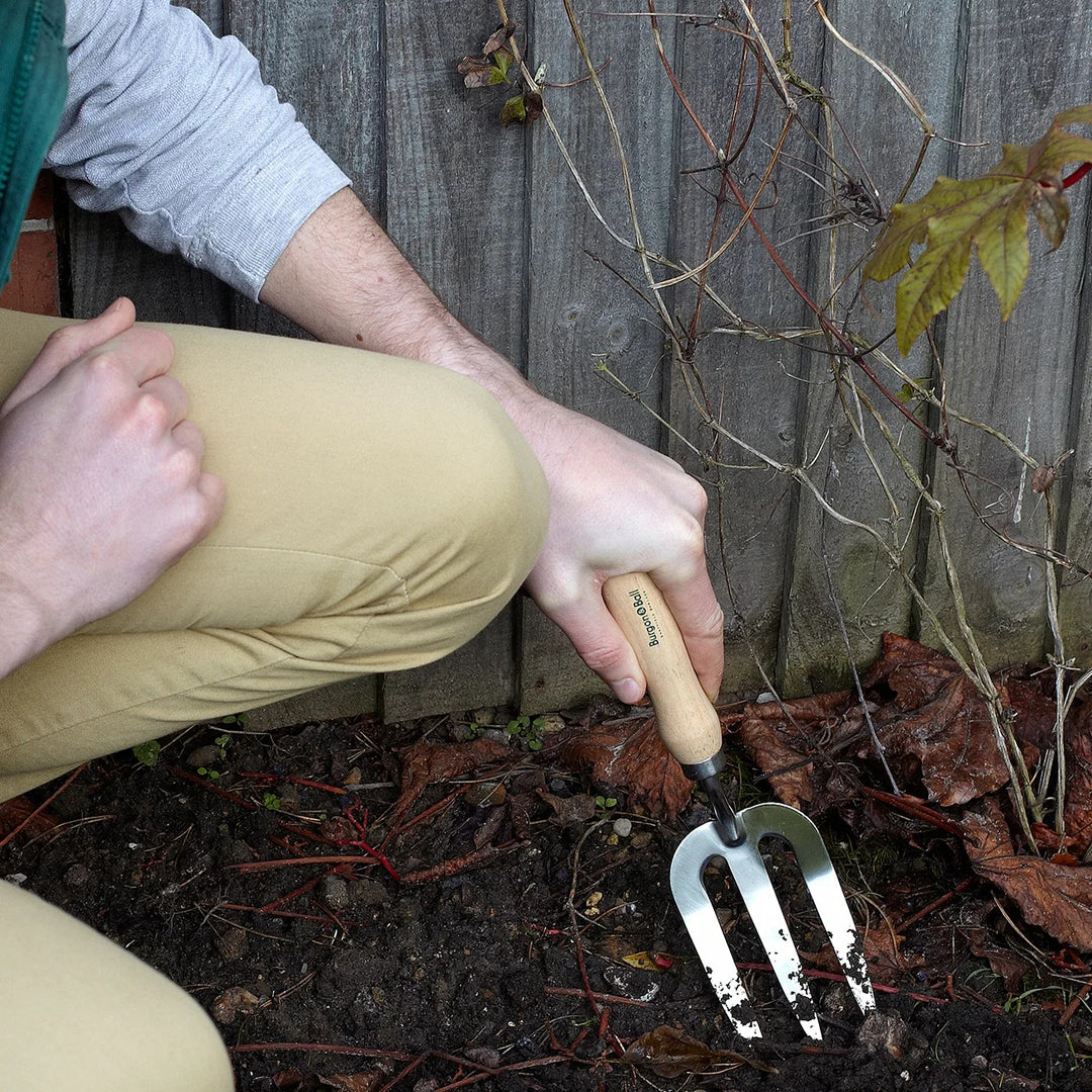Burgon & Ball RHS Endorsed Stainless Steel Gardening Hand Fork, in use loosening soil in a garden border