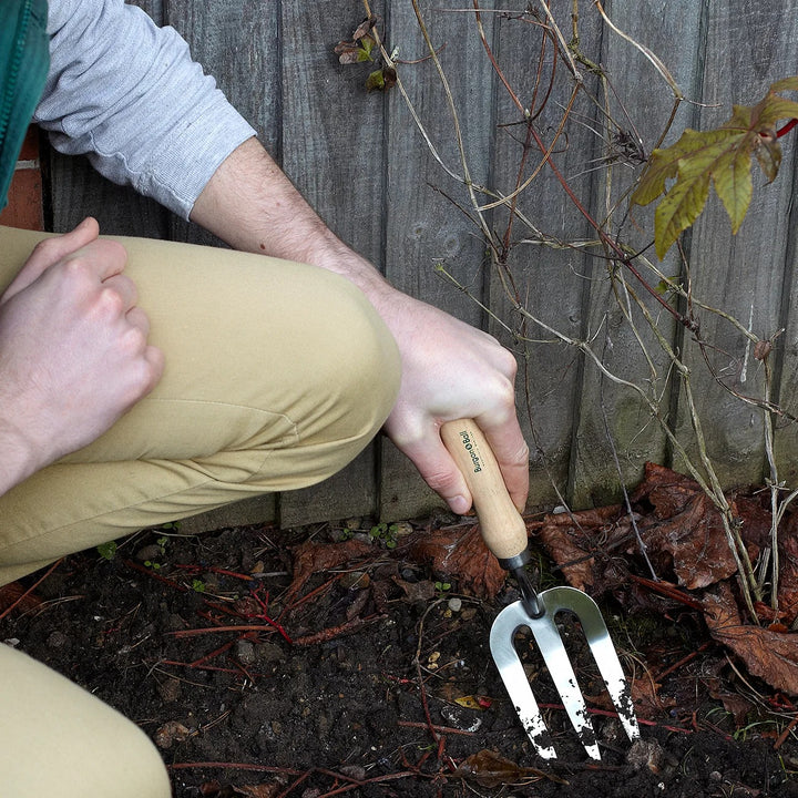 Burgon &amp; Ball RHS Endorsed Stainless Steel Gardening Hand Fork, in use loosening soil in a garden border