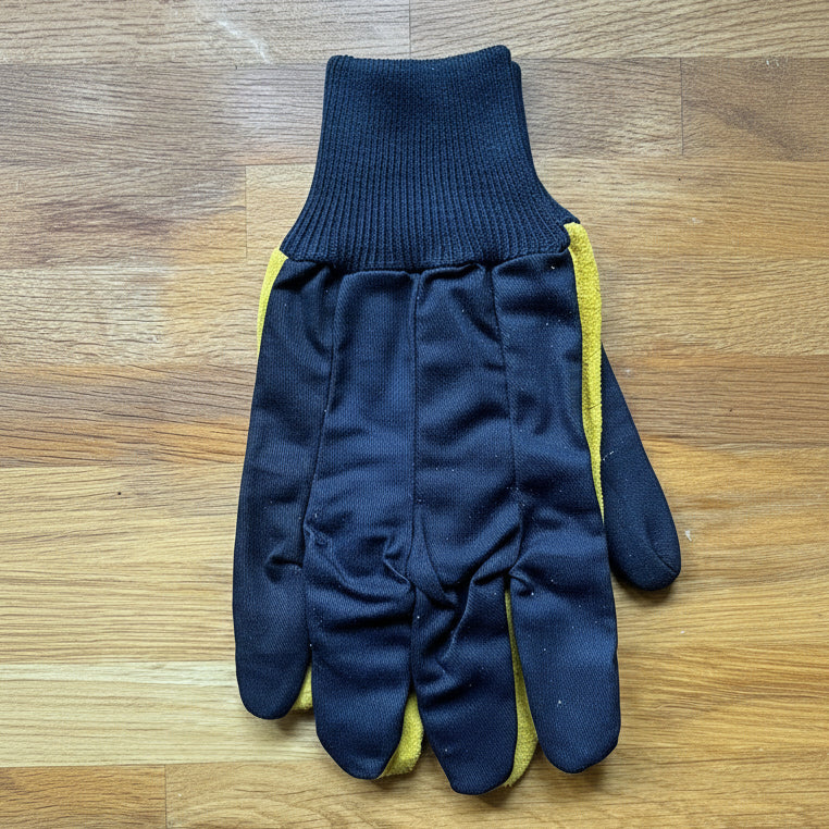 Pair of navy blue gloves with yellow suede palms on a wooden surface