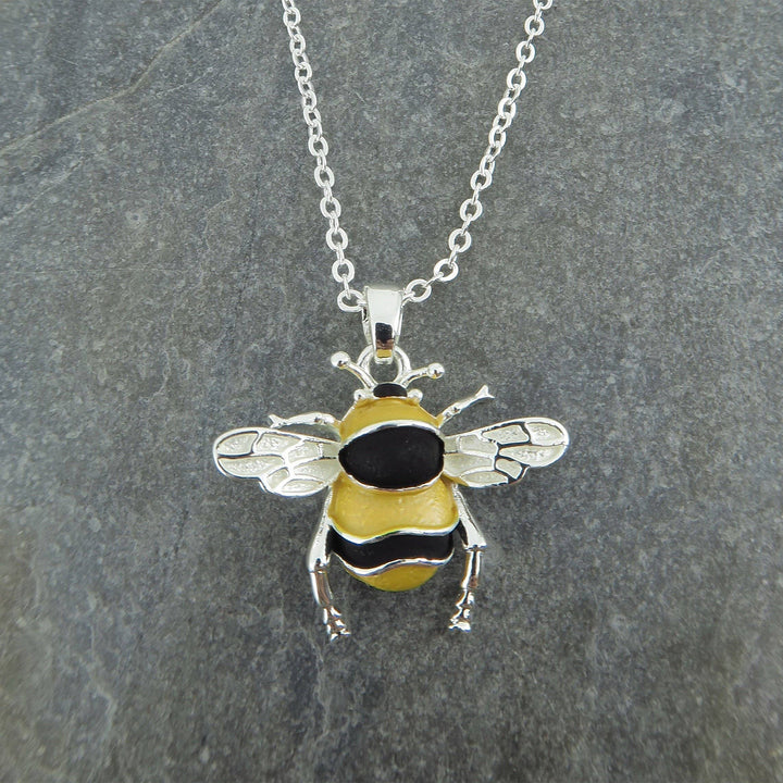 Bee-shaped pendant on a chain against a gray background