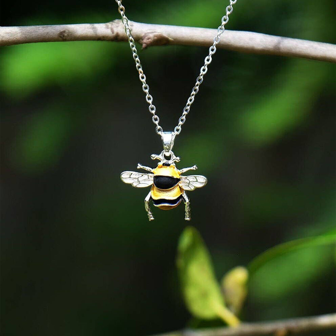 Bee-shaped pendant on a chain against a natural background