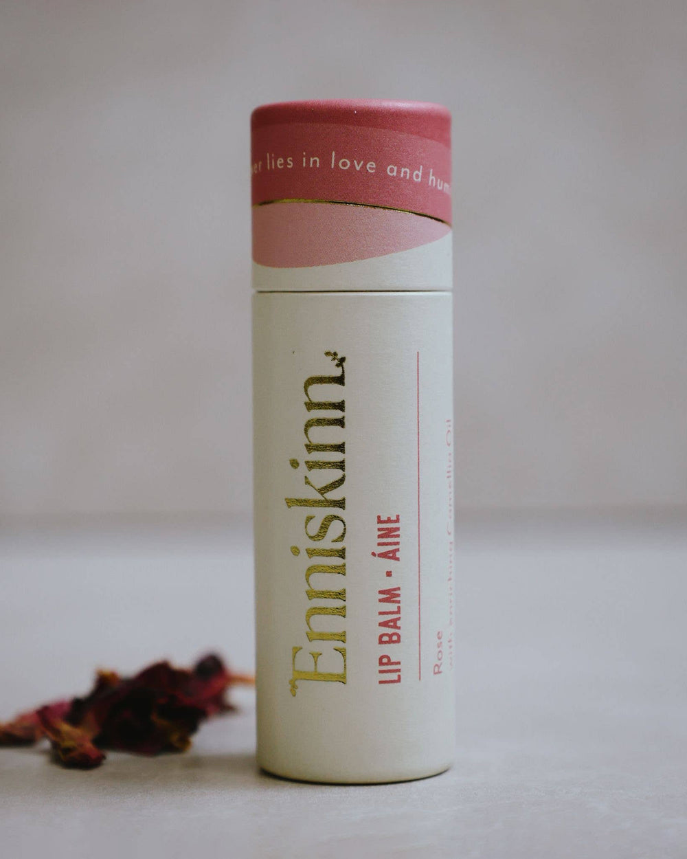 Lip balm container with 'Enniaskin' branding on a neutral background