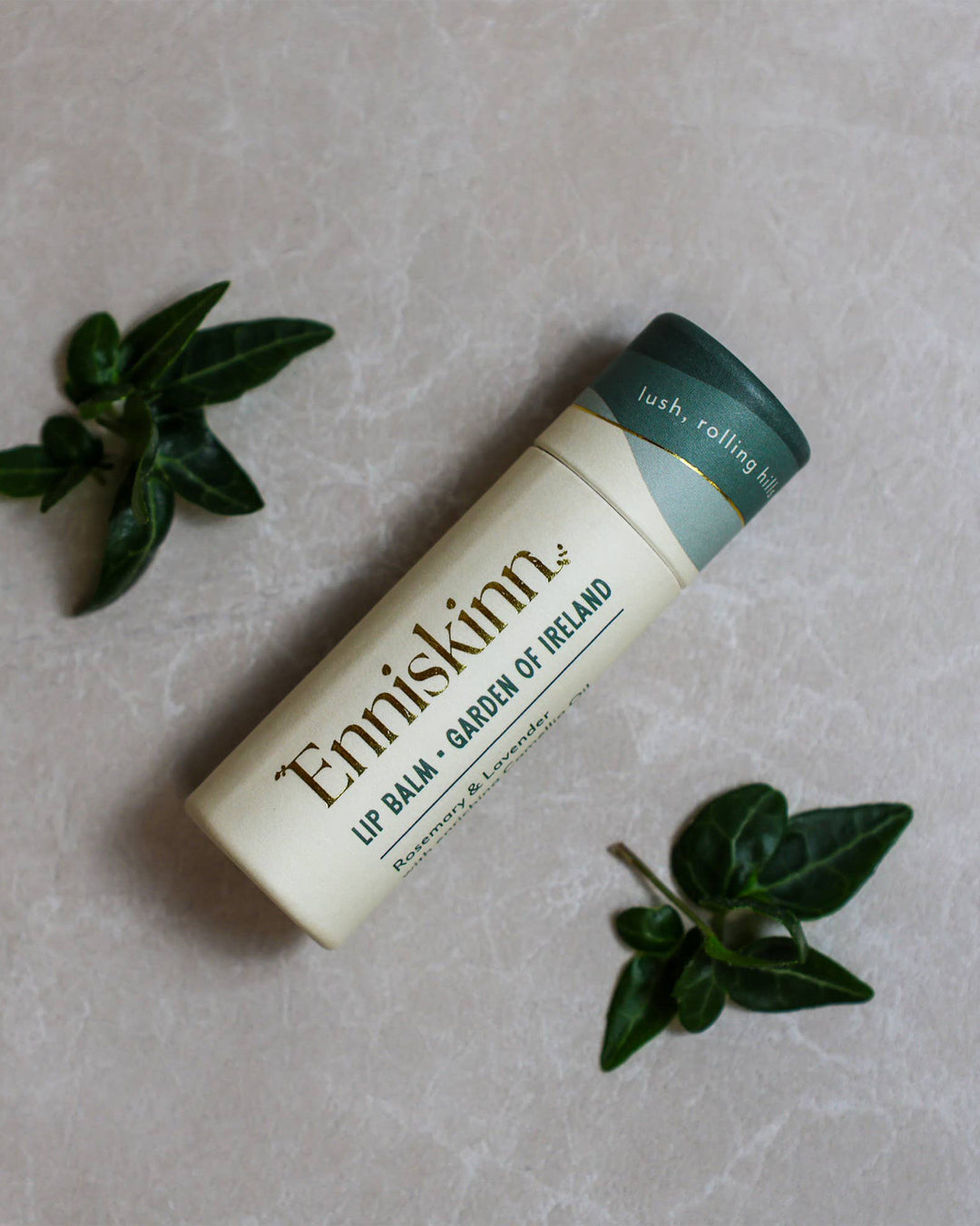 Enniskinn lip balm on a light gray background with green leaves