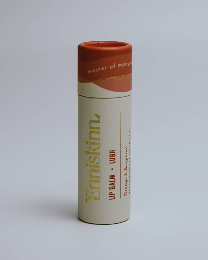 Lip balm tube with visible branding on a gray background
