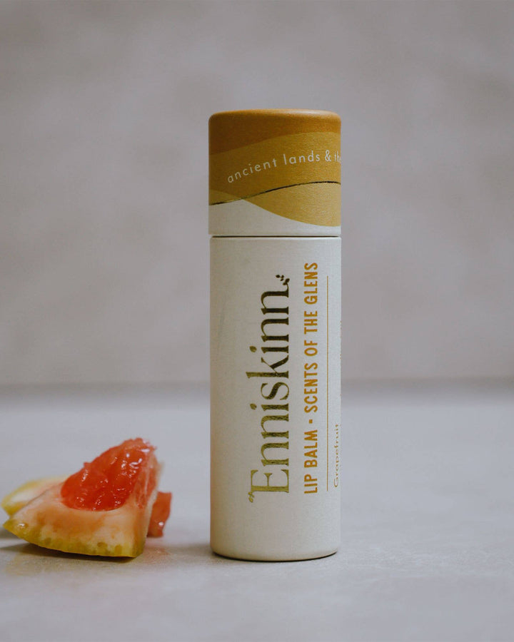 Enniskinn lip balm container with a piece of grapefruit on a light background