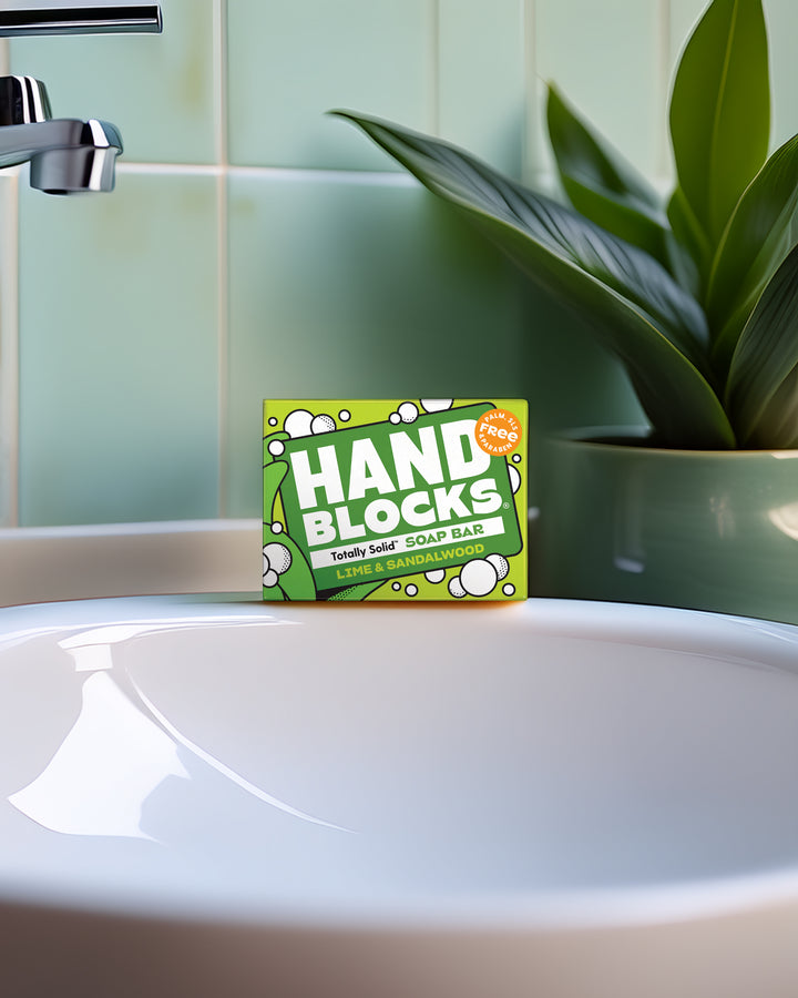 Hand Blocks soap bar packaging on a bathroom sink with a plant in the background