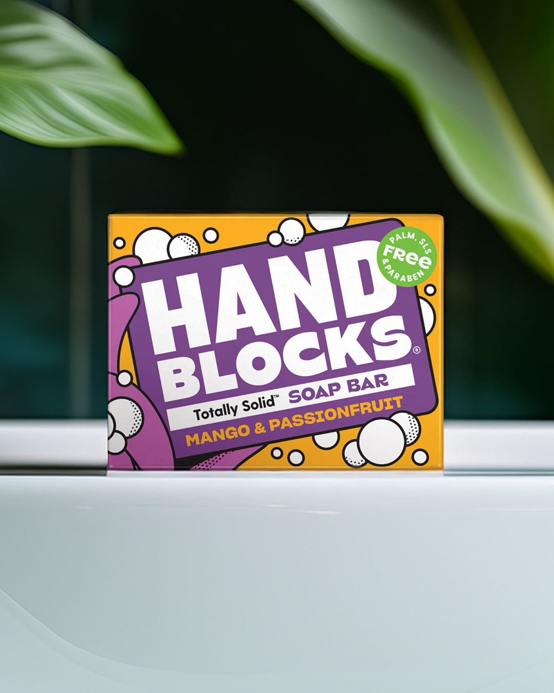 Hand Blocks soap bar packaging on a white surface with green leaves in the background
