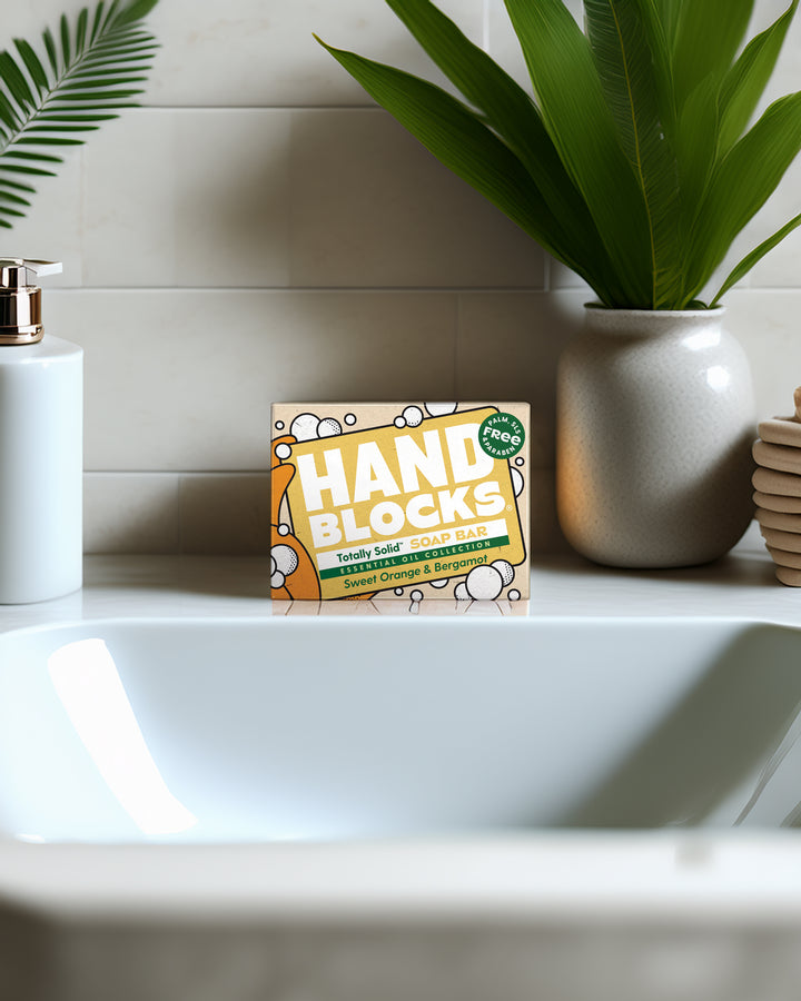 Hand Blocke packaging on a bathroom counter with a plant and soap dispenser in the background.