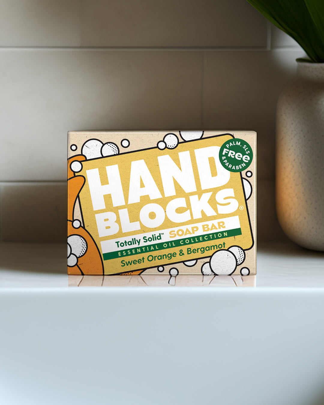 Box of Hand Blocks soap bar on a bathroom shelf with a plant in the background