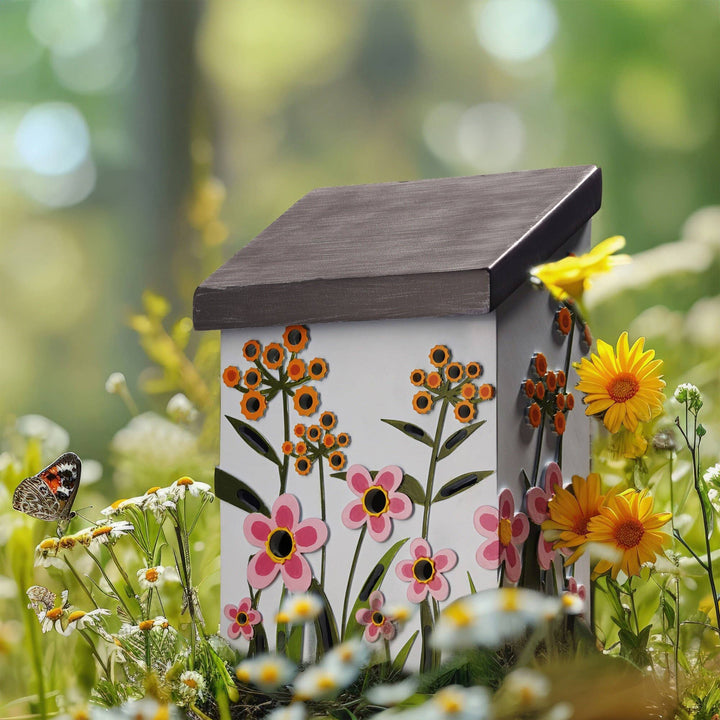 Decorative bee house with floral design in a garden setting