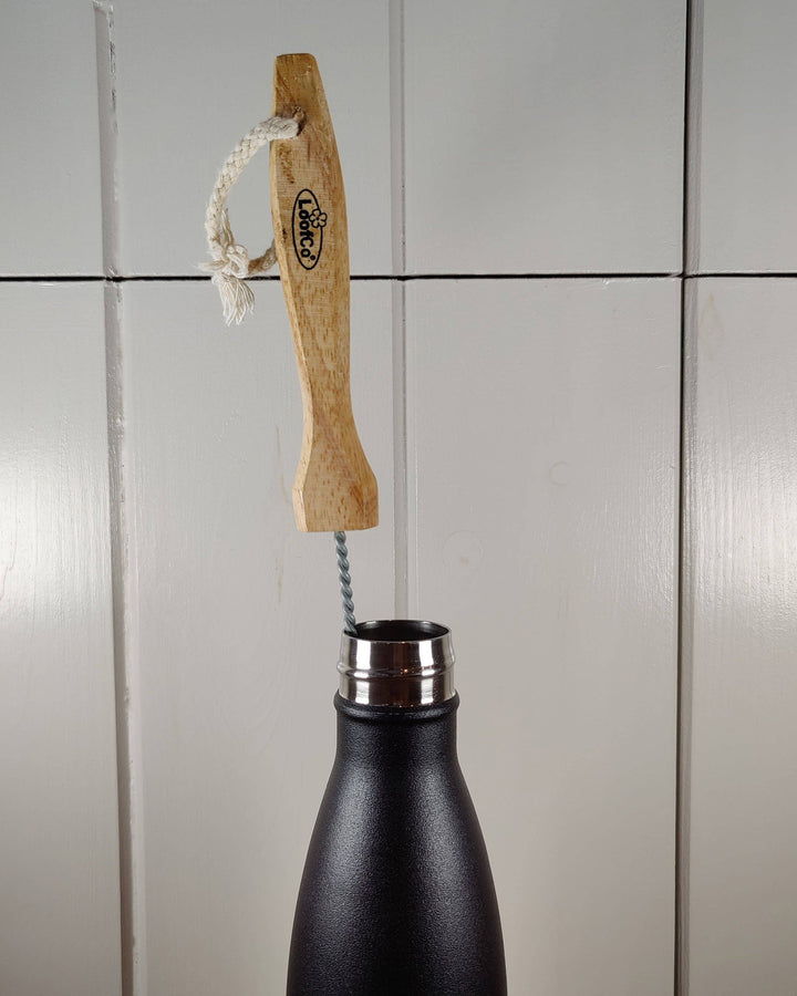 Black bottle with wooden brush against a tiled wall background