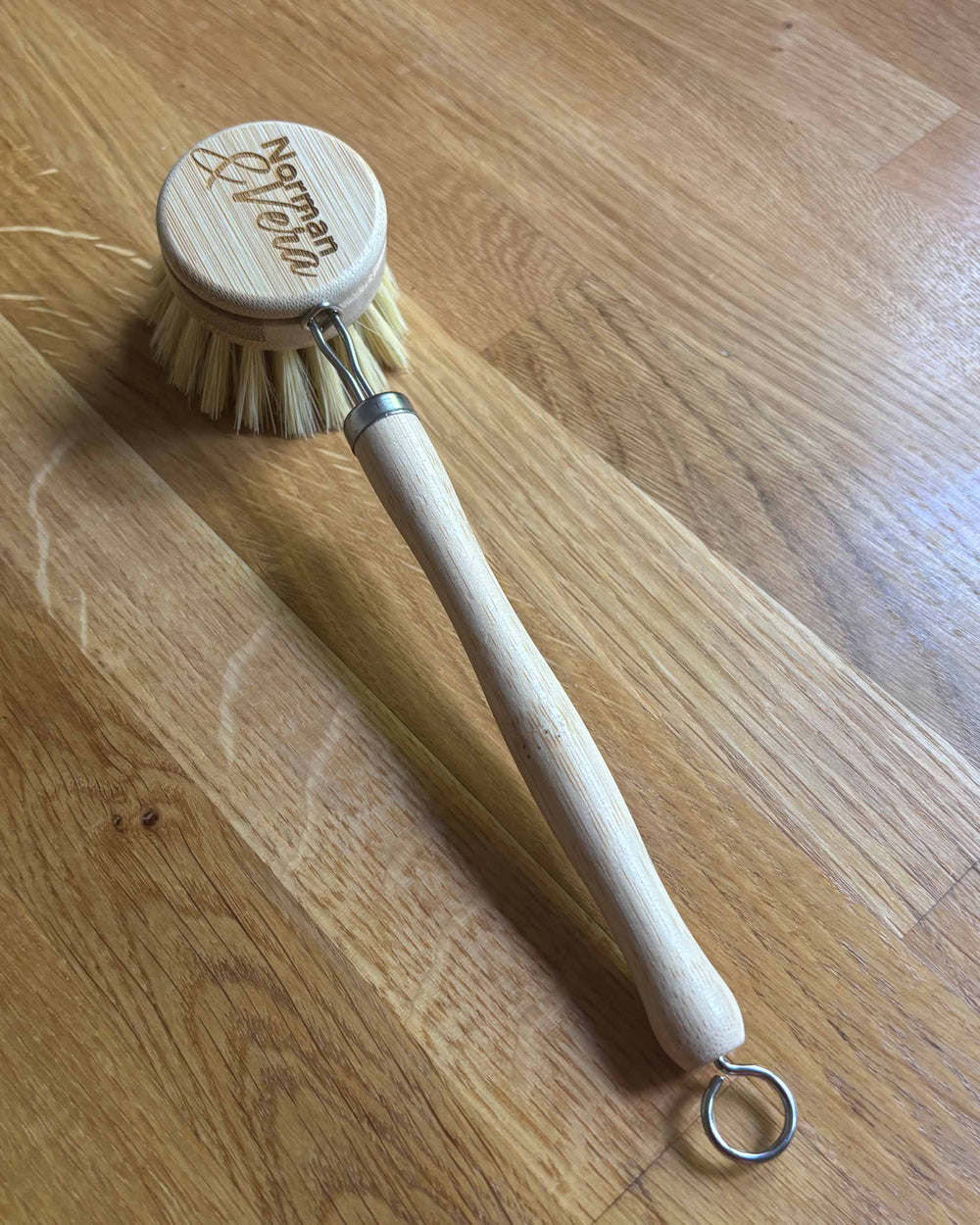 Dish brush with wooden handle and round head on a wooden surface