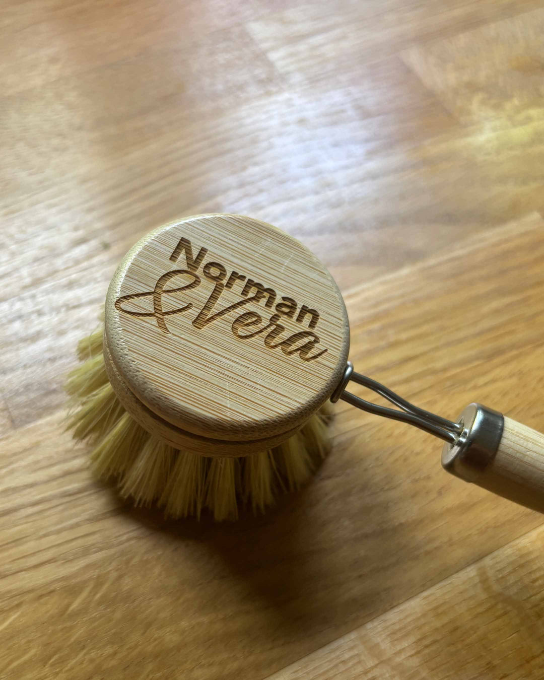 Wooden dish brush with 'Norman & Vera' branding on a wooden surface