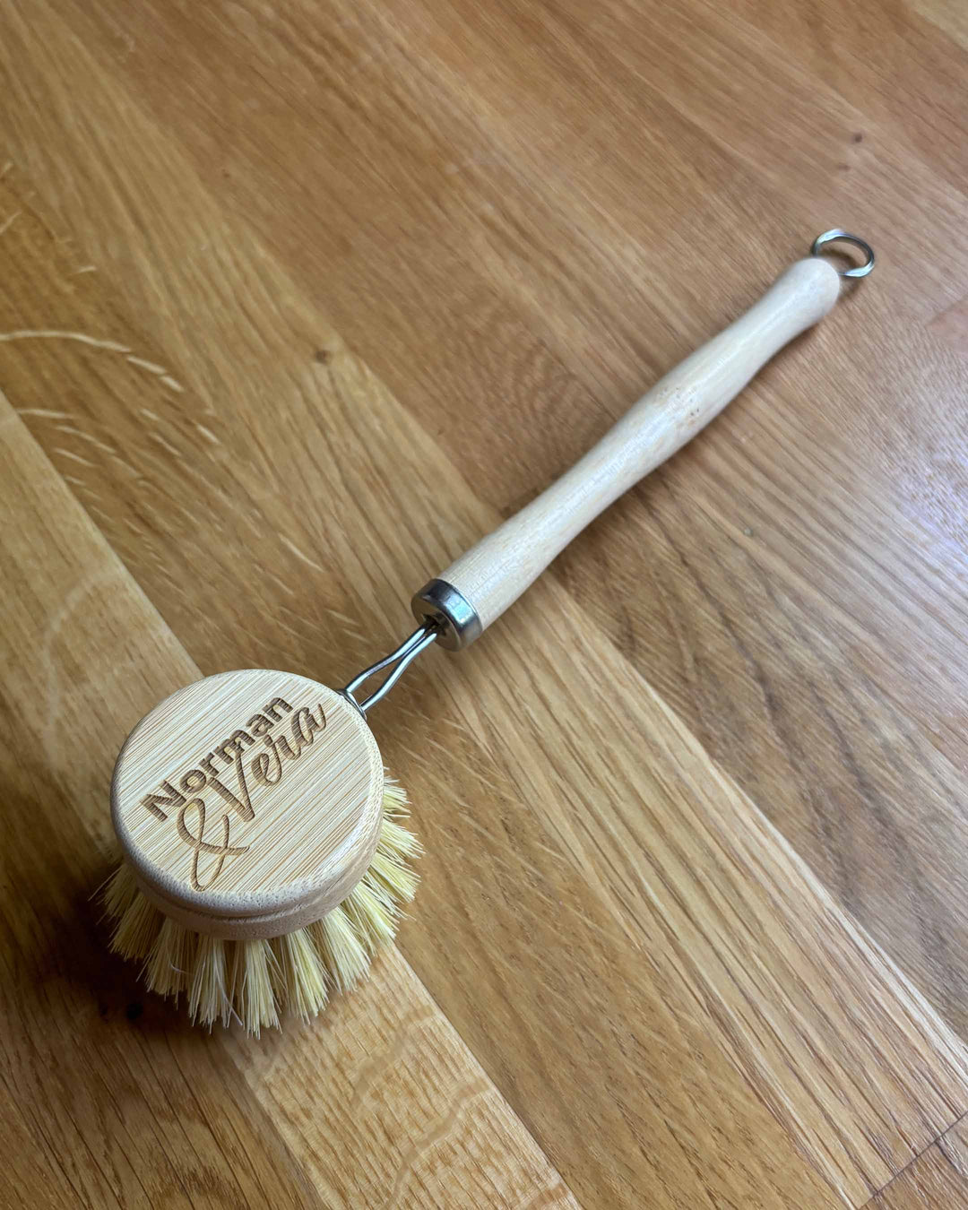 Wooden dish brush with a round head and handle on a wooden surface