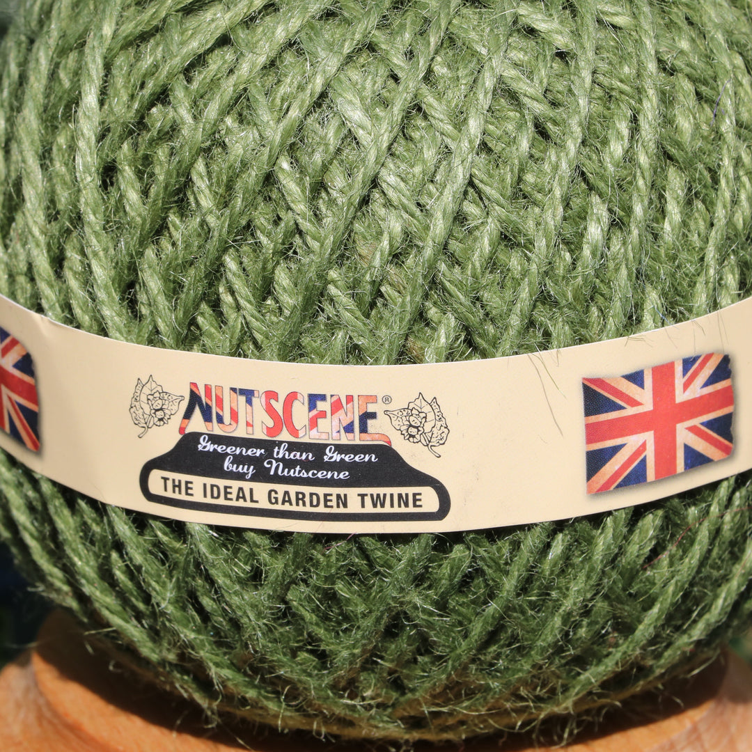 A close-up of a green ball of yarn wrapped with a paper band labeled &