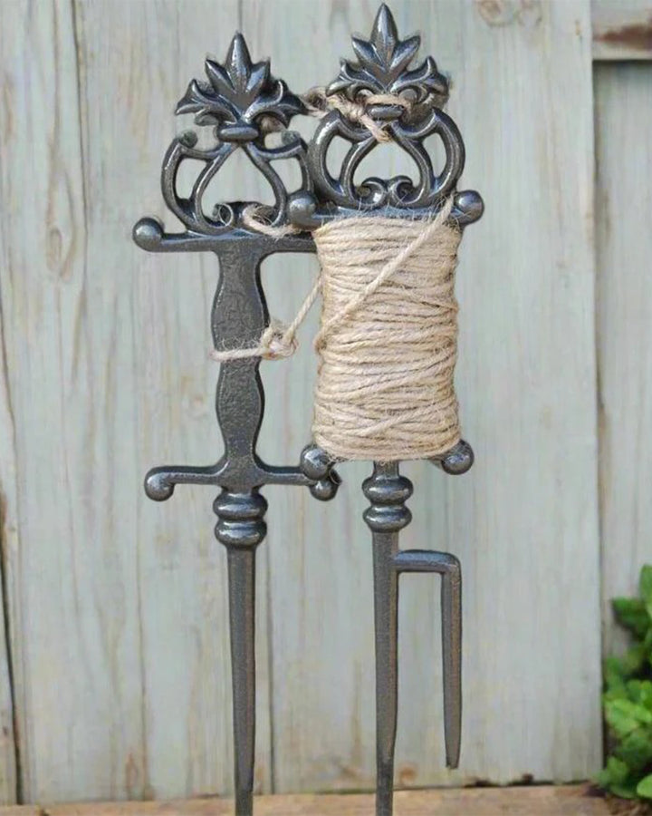 Decorative metal holder with a spool of twine against a wooden background