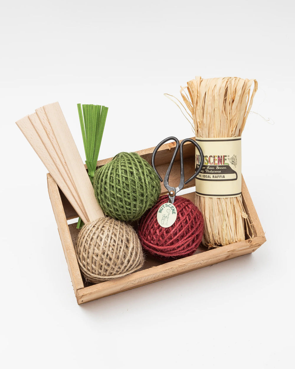 Set of decorative items including a ball, scissors, and a bundle of twigs in a wooden box on a white background.