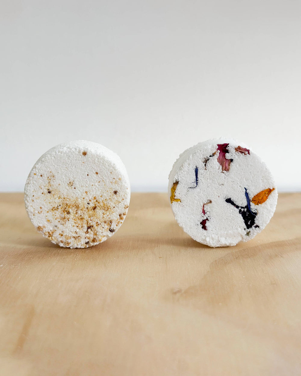 Two round bath bombs with decorative designs on a marble surface