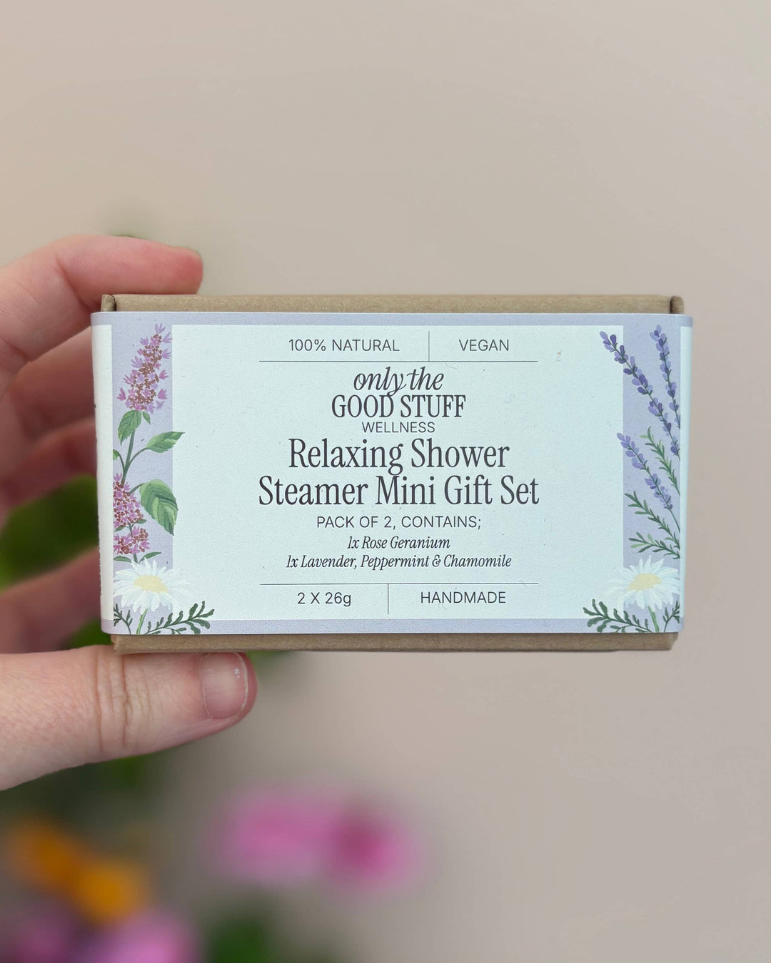 Hand holding a 'only the good stuff' relaxing shower steamer mini gift set against a neutral background.