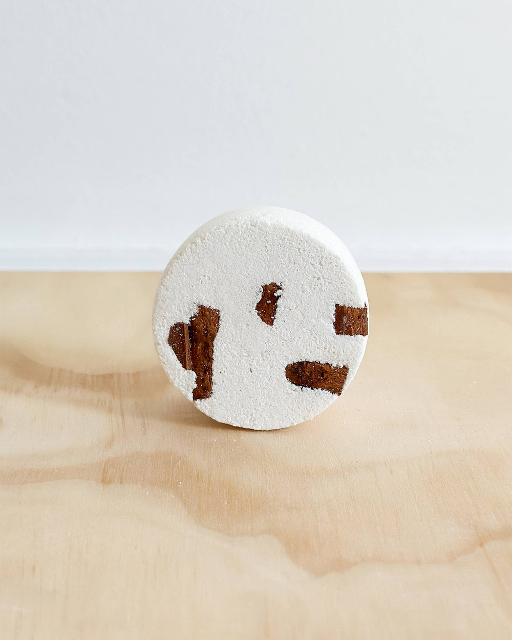 Round bath bomb with brown paw prints on a marble surface