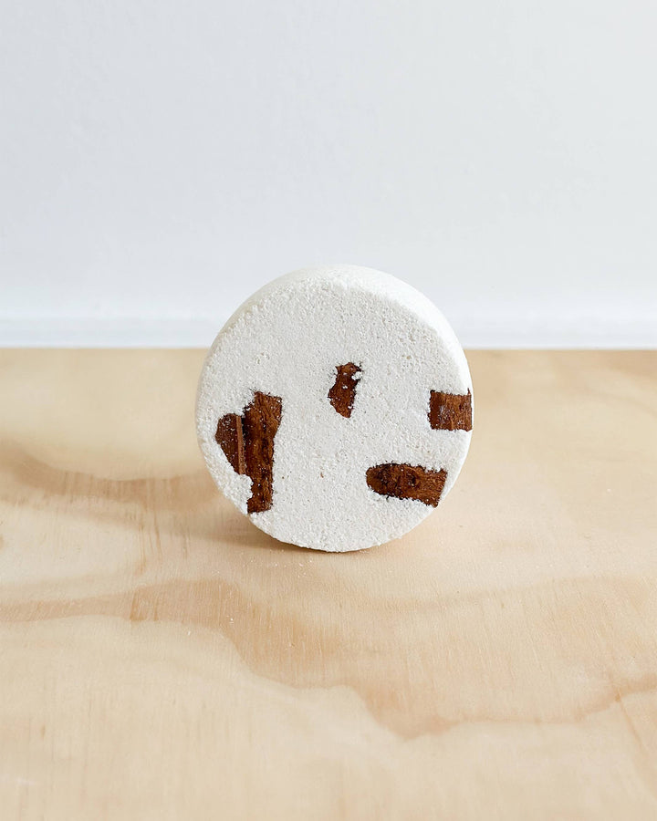 Round bath bomb with brown paw prints on a marble surface