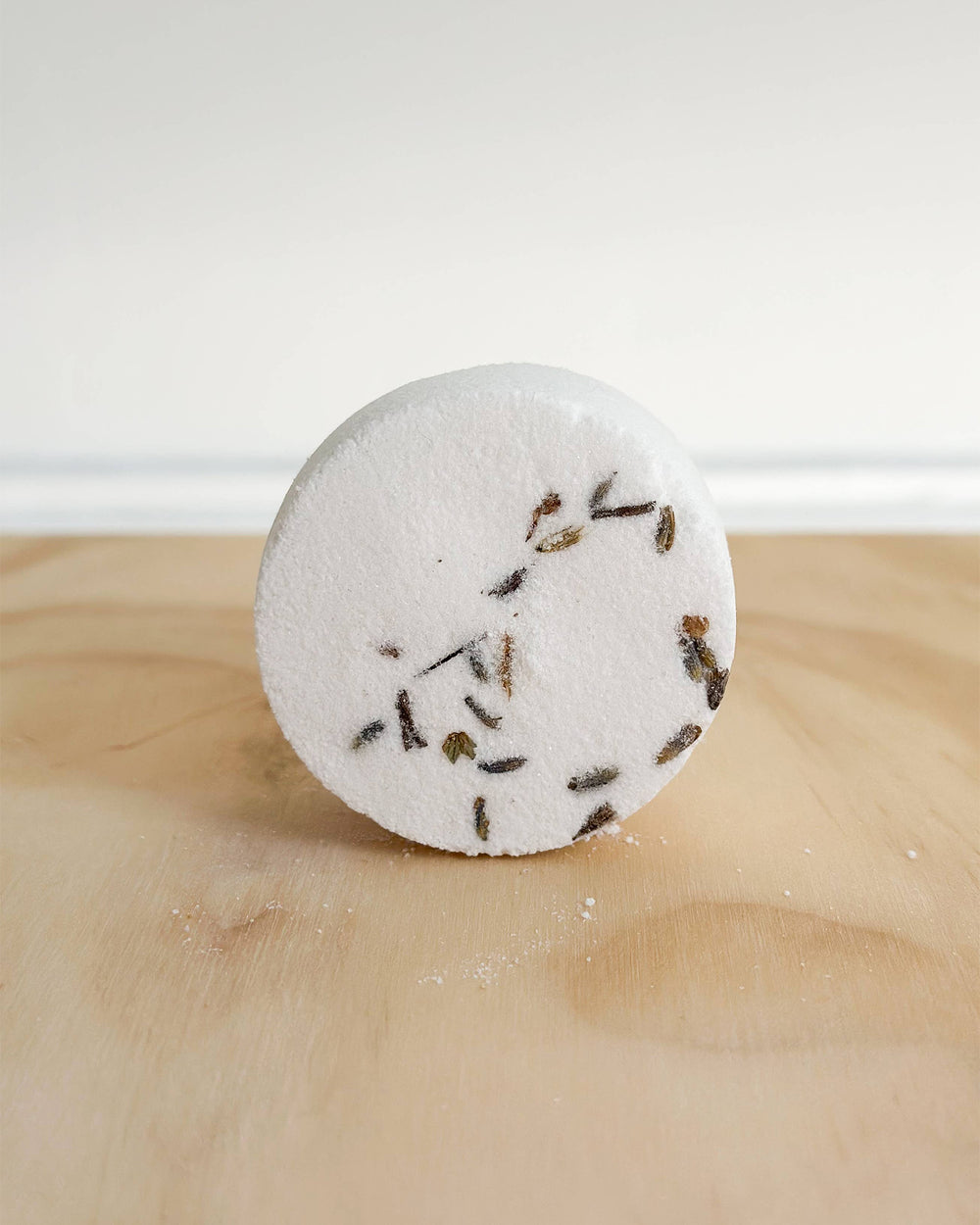 Round bath bomb with lavender buds on a wooden surface