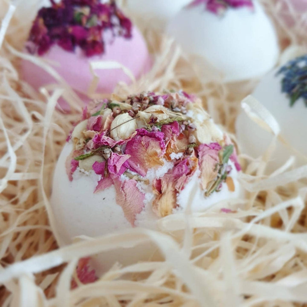 Decorative bath bombs with floral elements on a bed of straw