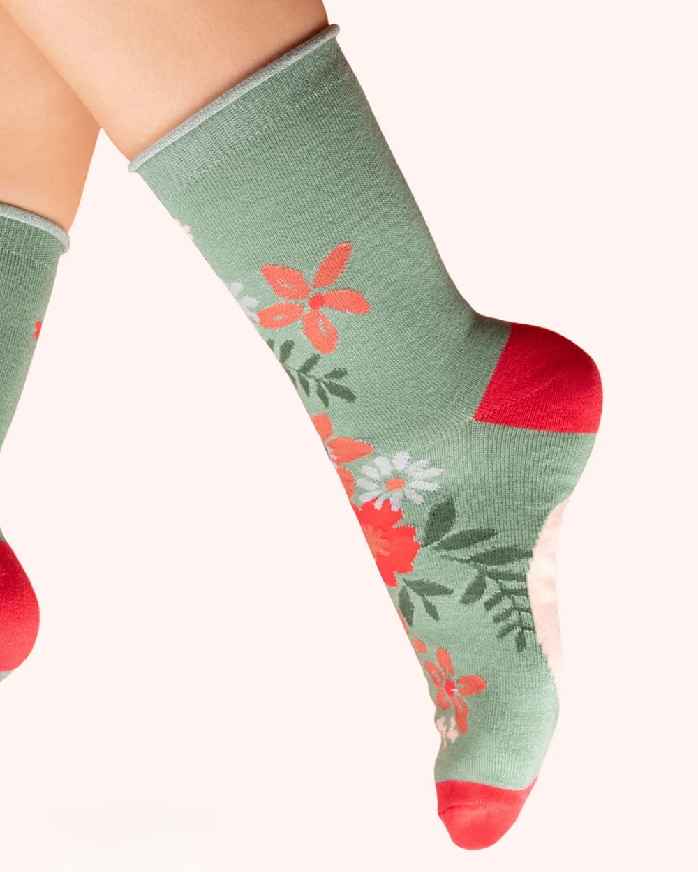 Green sock with floral pattern worn by a person on a white background