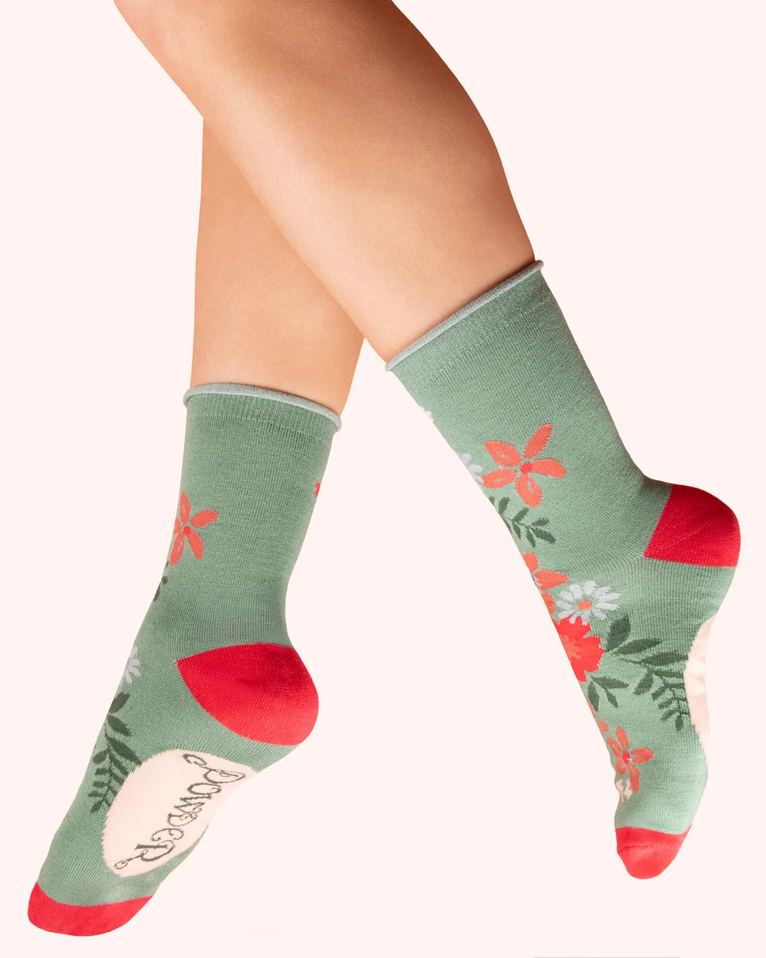 Green socks with floral patterns worn by a person on a white background