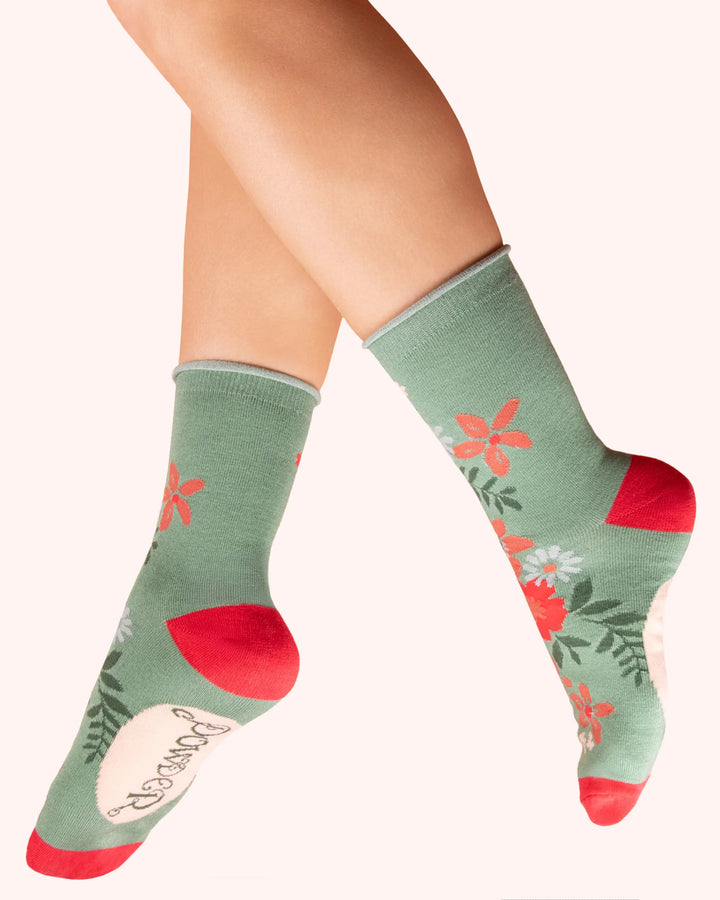 Green socks with floral patterns worn by a person on a white background