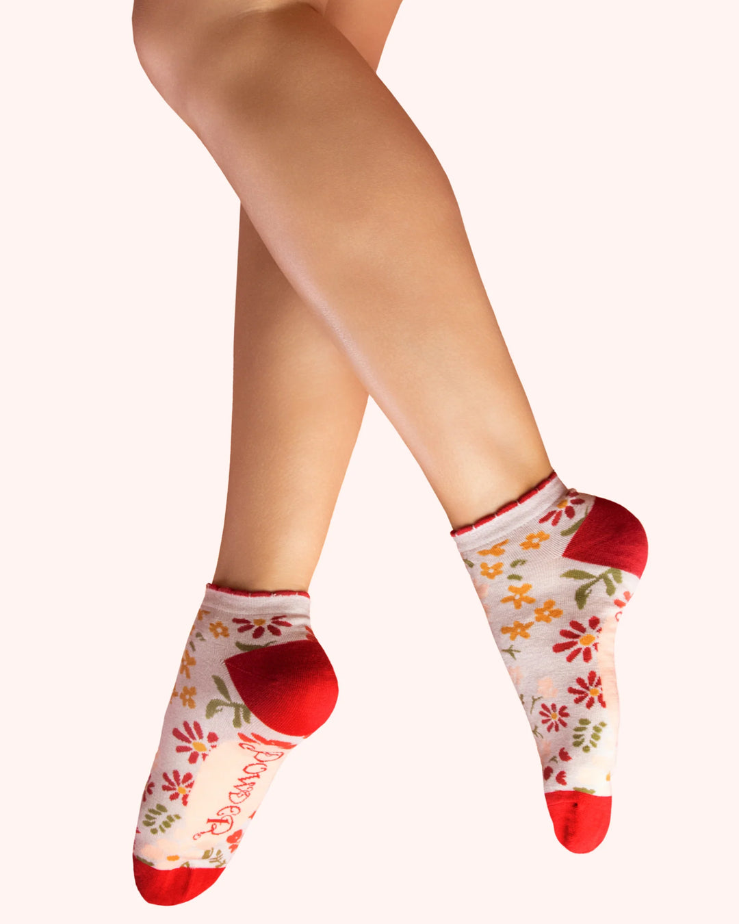 Floral-patterned socks with red toes and cuffs worn by a person on a white background