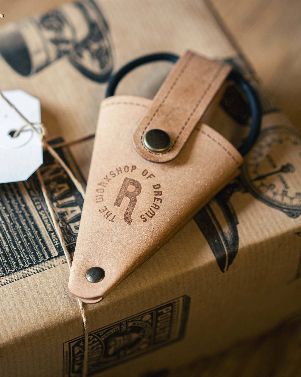 Leather pouch with 'The Workshop of Dreams' branding on a cardboard surface.