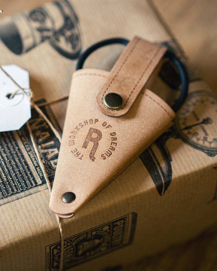 Leather pouch with 'The Workshop of Dreams' branding on a cardboard surface.