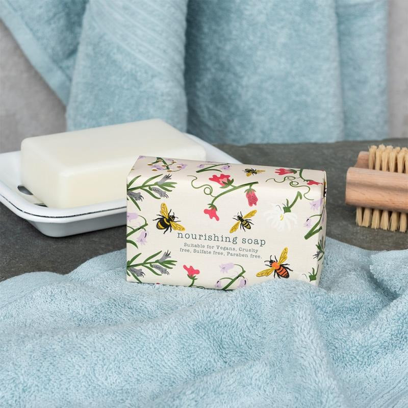 Nourishing soap bar with floral packaging on a blue towel