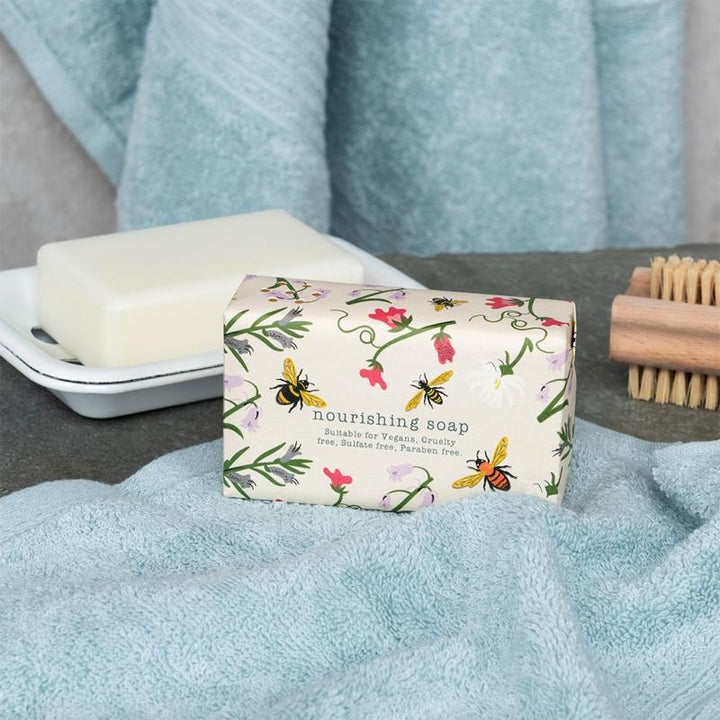 Nourishing soap bar with floral packaging on a blue towel