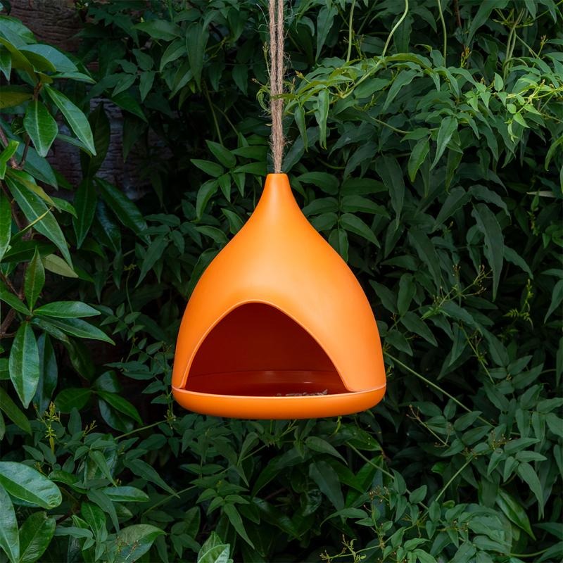 Orange hanging bird feeder against a green leafy background