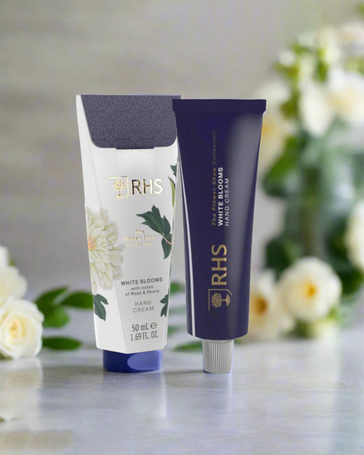 Two tubes of cream with 'RHS' branding on a surface with flowers in the background
