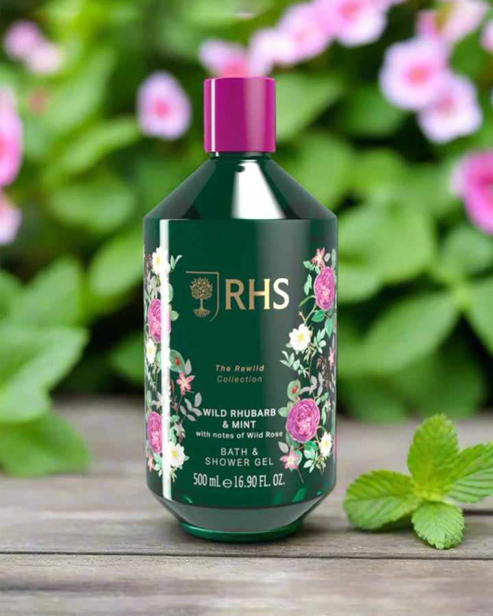Bottle of RHS bath and shower gel with floral design on a wooden surface with greenery in the background