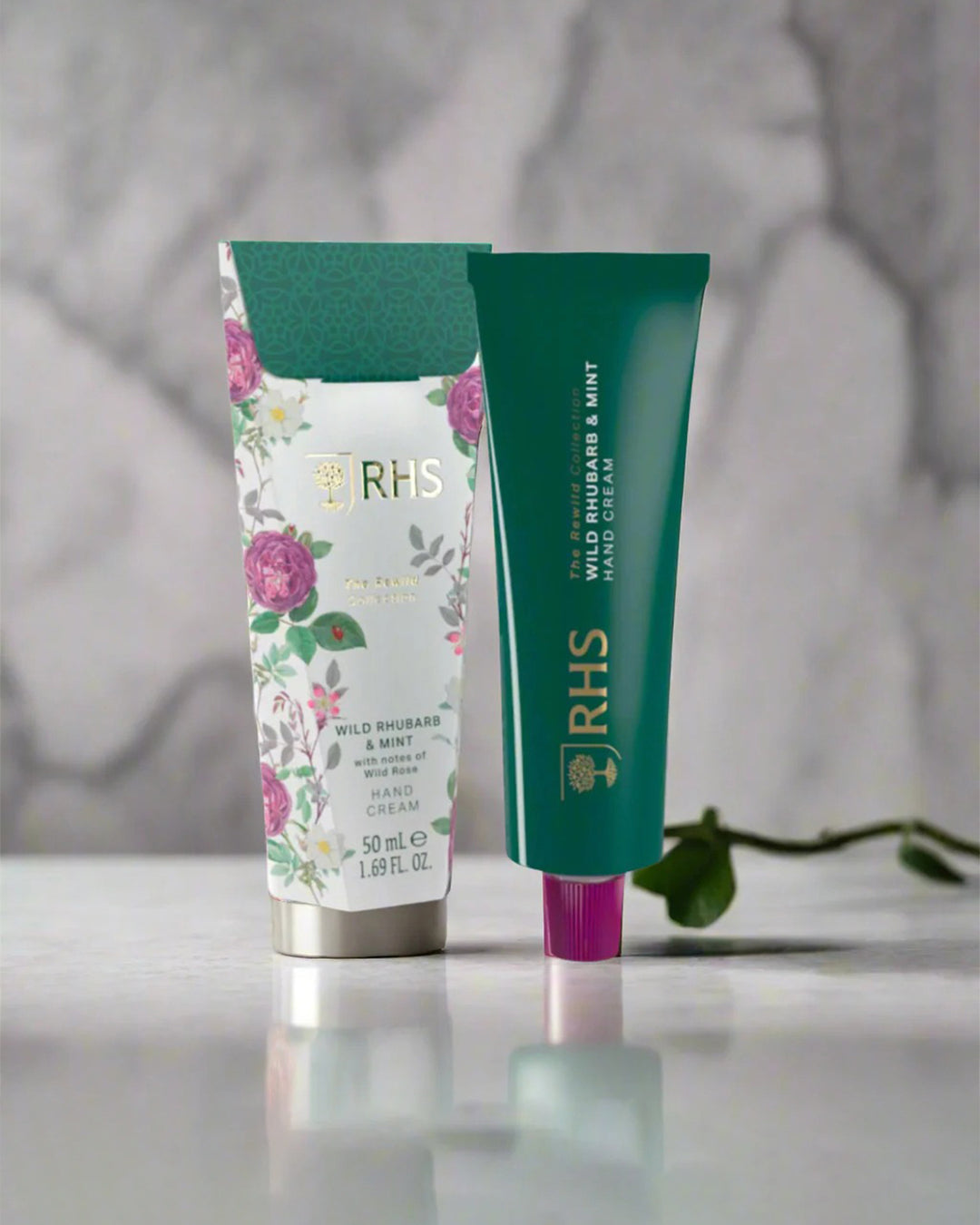 Two tubes of skincare products with floral design and green packaging on a neutral background