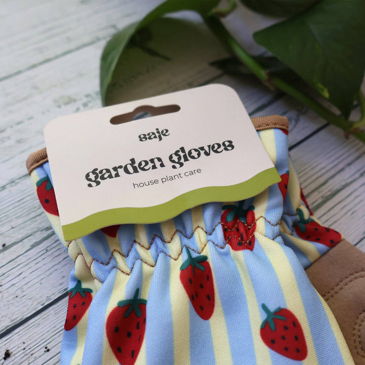 Gardening gloves with strawberry pattern on a wooden surface
