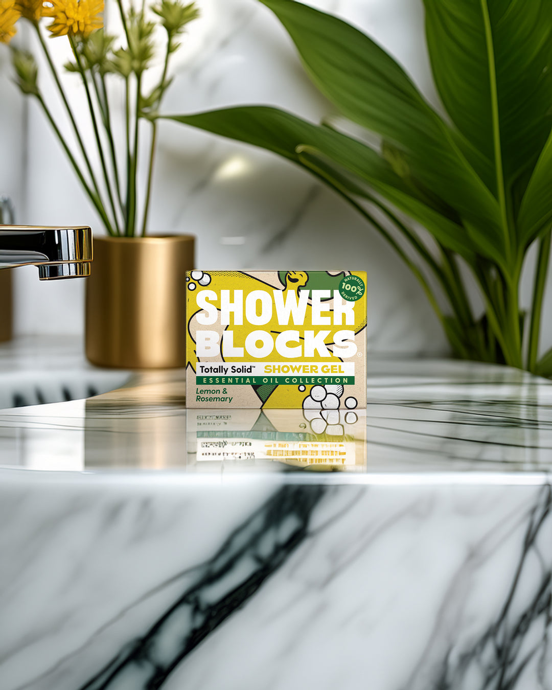 Pack of Shower Blocks on a marble surface with plants and a gold vase in the background