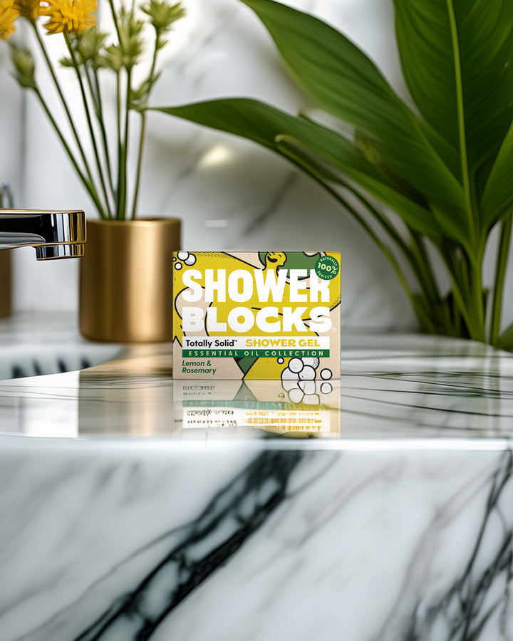 Pack of Shower Blocks on a marble surface with plants and a gold vase in the background