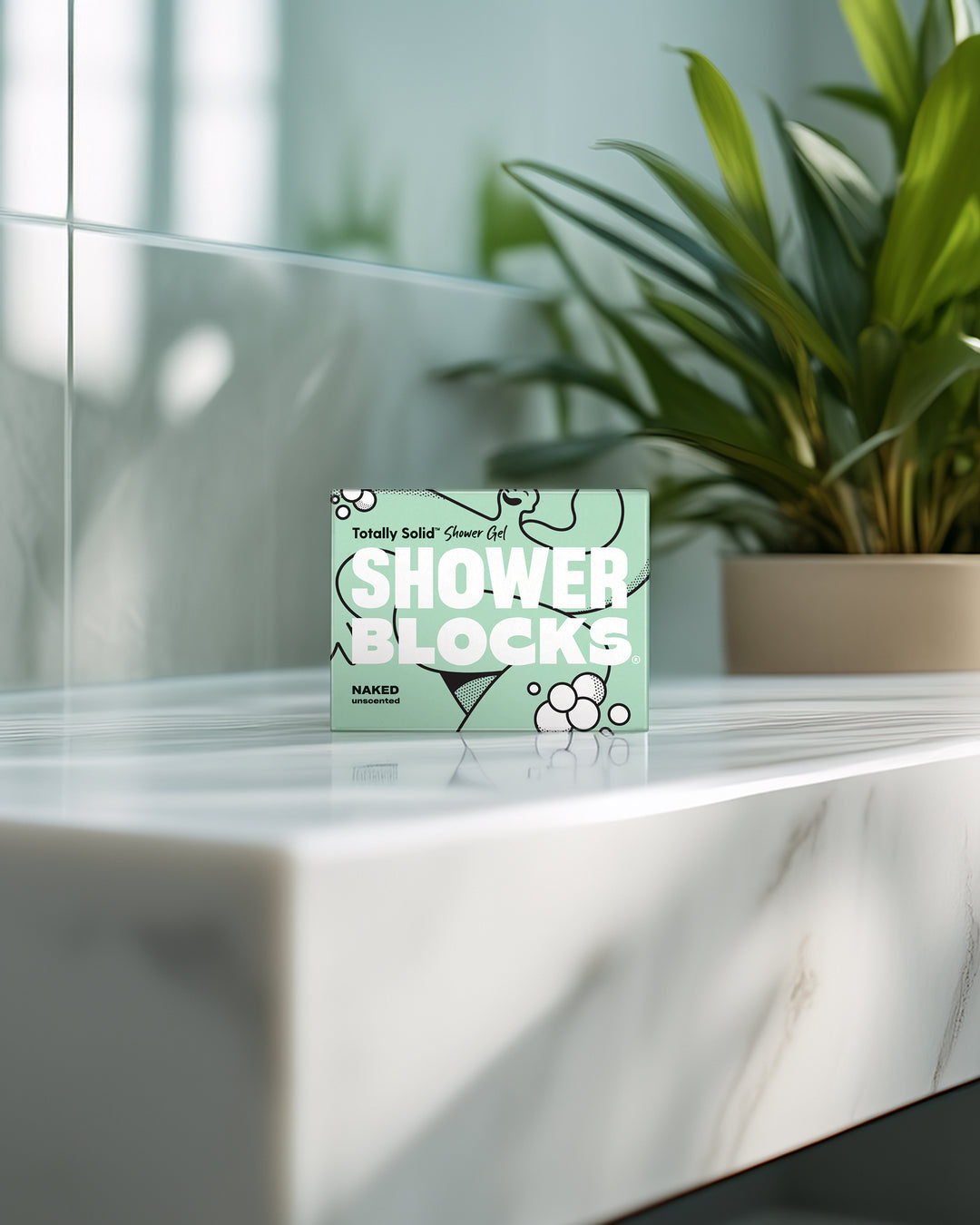Box of 'Shower Blocks' on a marble surface with a plant in the background