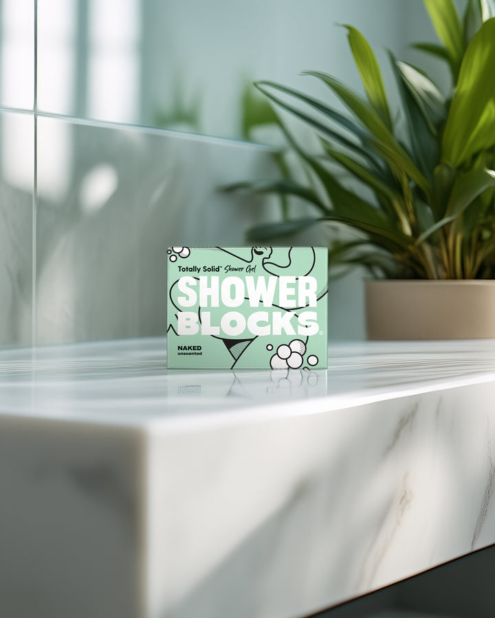 Box of 'Shower Blocks' on a marble surface with a plant in the background