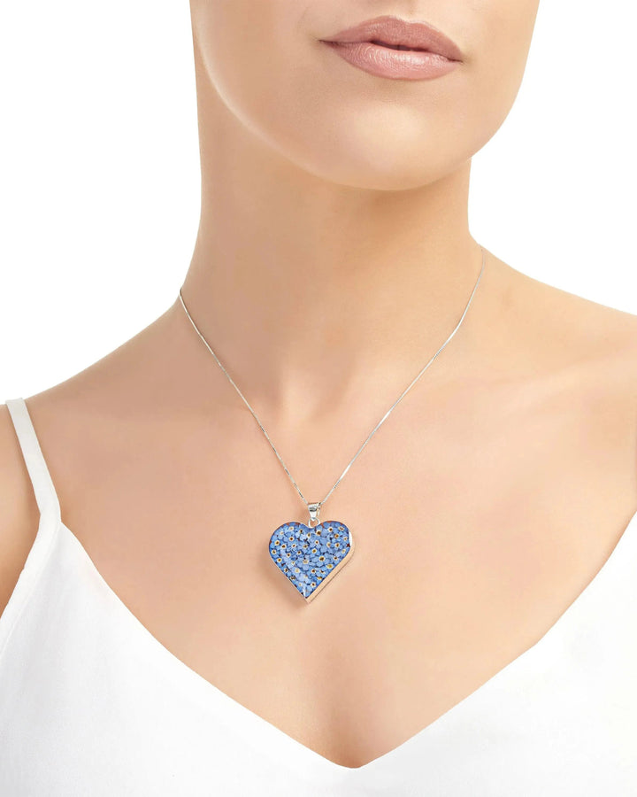 Blue heart-shaped pendant on a silver chain worn by a model against a white background