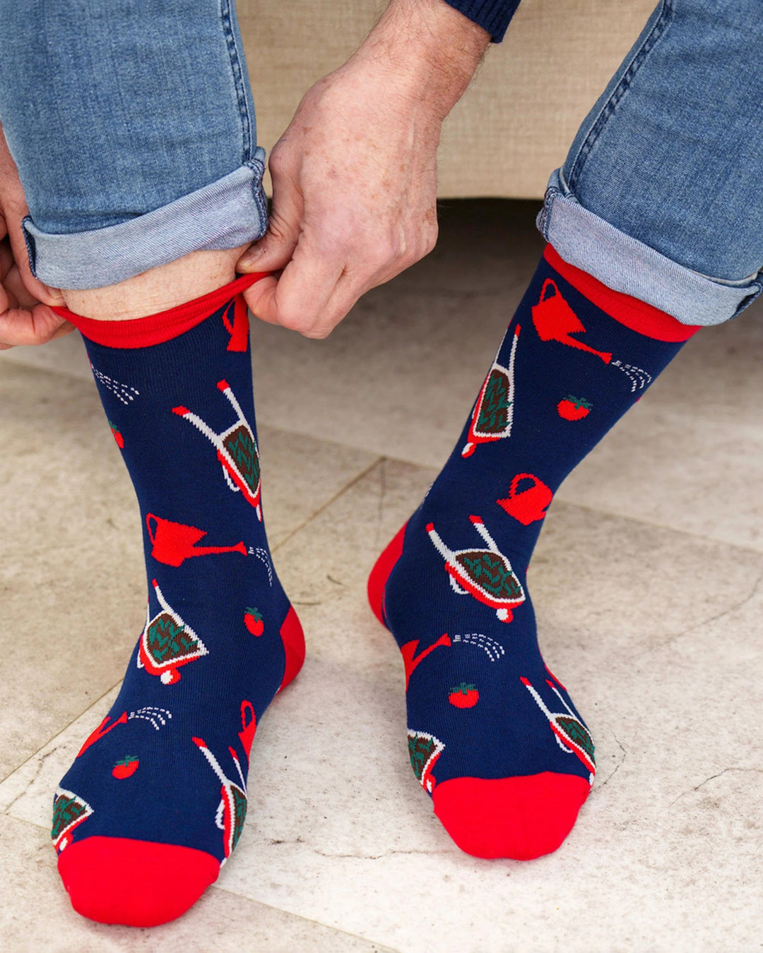 Person wearing navy socks with red accents and garden-themed designs on a light background.
